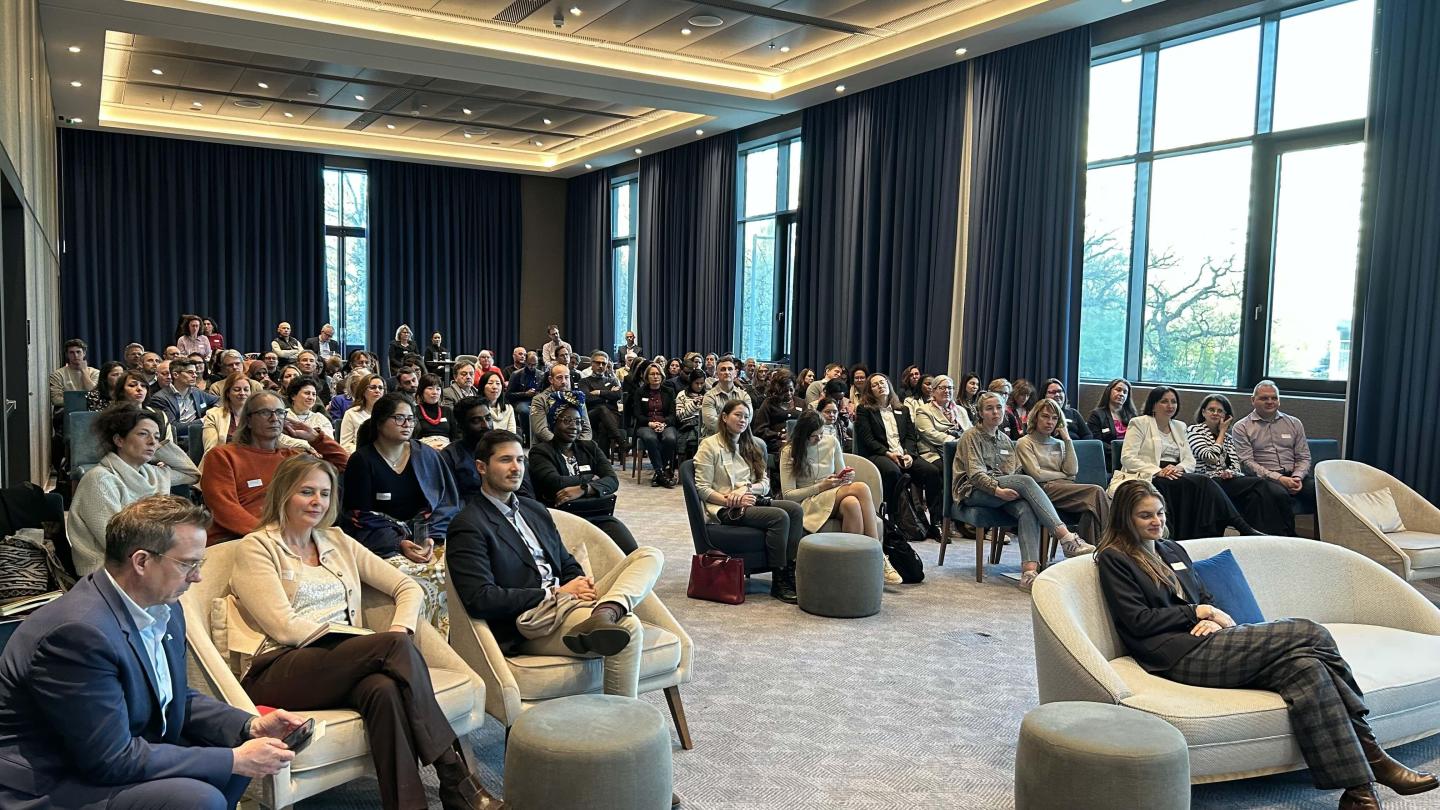 Salle avec une centaine de participants écoutant les témoignages